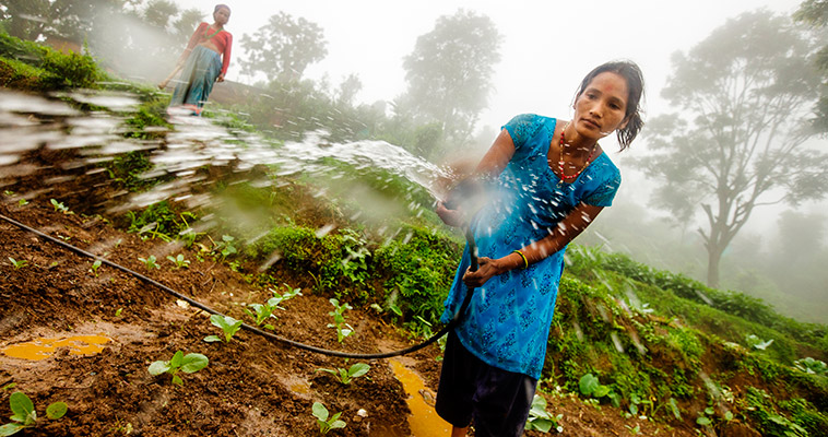 Photo of Sapana Bhattarai, a farmer in Nepal, spraying a hose.