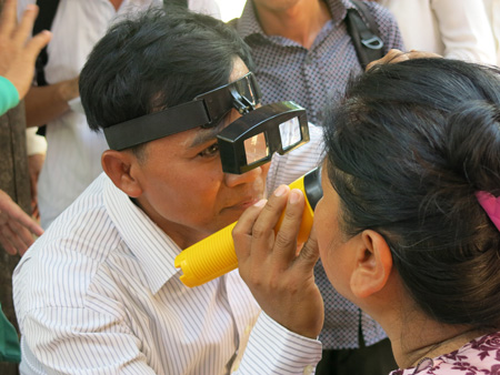 A doctor checks the eyes  of a woman in Cambodia