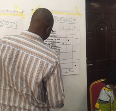 A man writes on a whiteboard during a FMoH presentation.