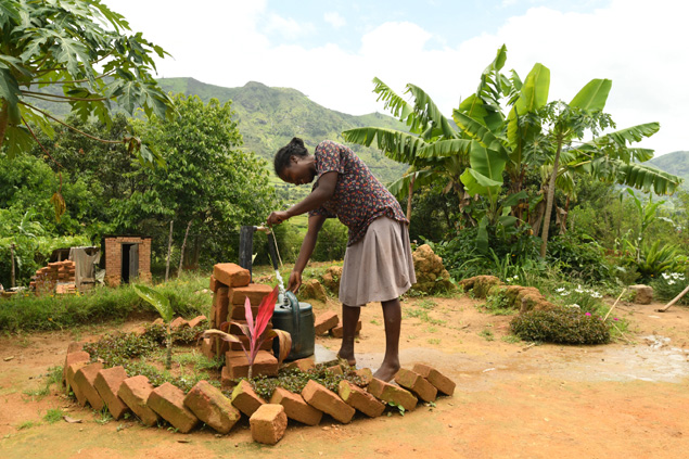 A woman uses a hand pump for clean water.
