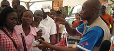 A man demonstrates a condom at an information booth.