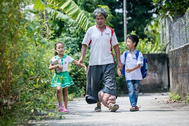Truong Van Duc and his grandchildren walk through their village.