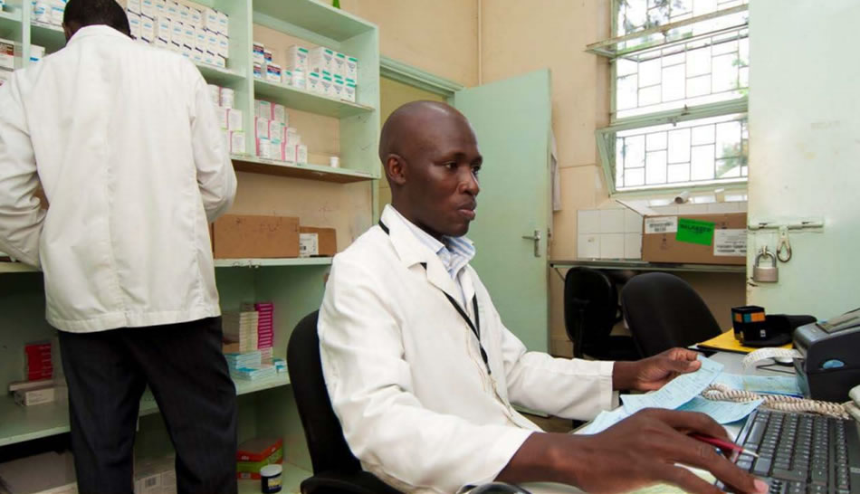 Jude Odhiambo enters prescriptions into the Antiretroviral Dispensing Tool as his colleague Sosten Kemboi picks the medicines from the shelf at the adult pharmacy at the Kenyatta National Hospital Comprehensive Care Center.