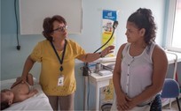 A medical professional examines a child while speaking to a mother.