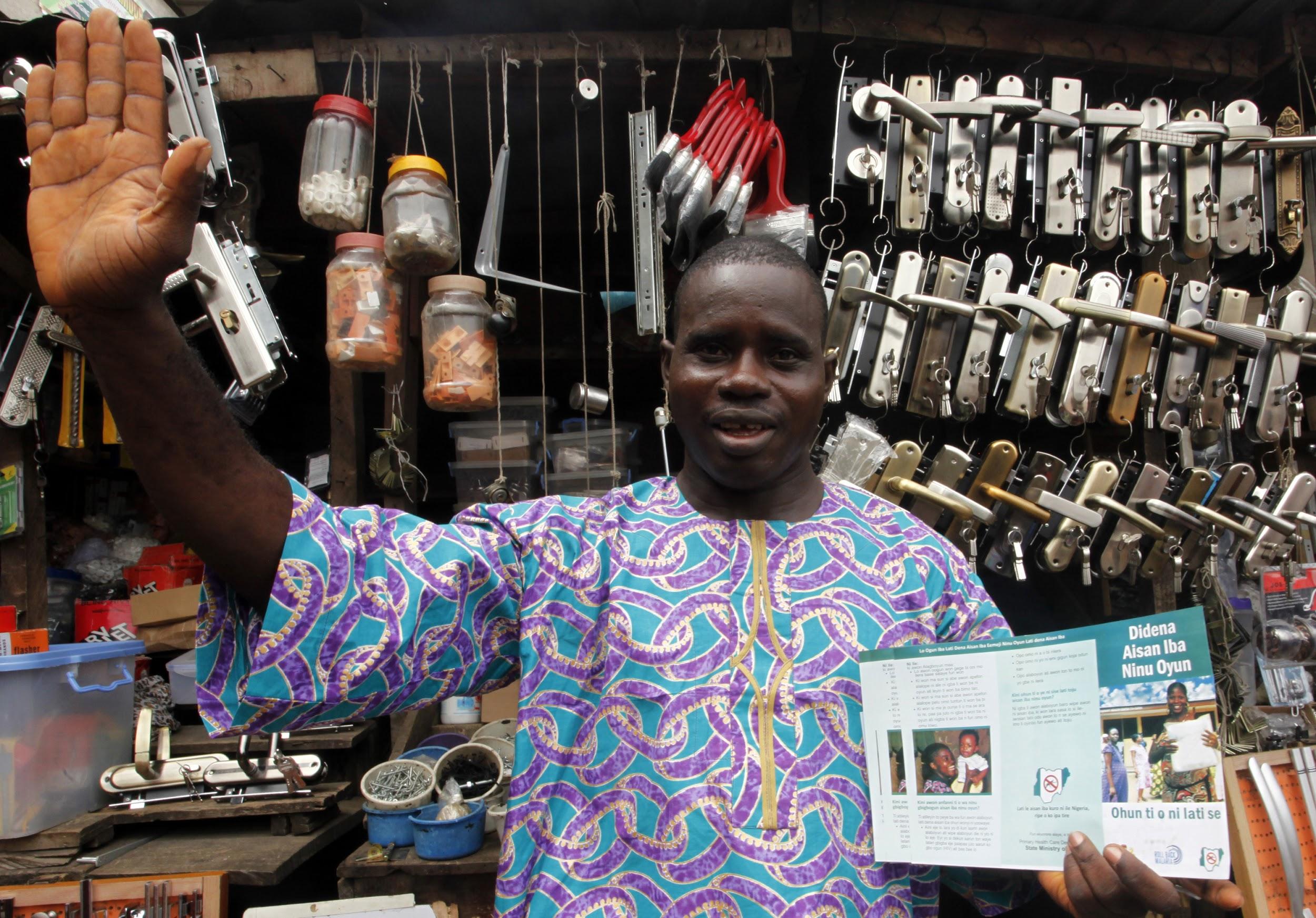 A store owner in Nigeria shows a malaria prevention flyer.