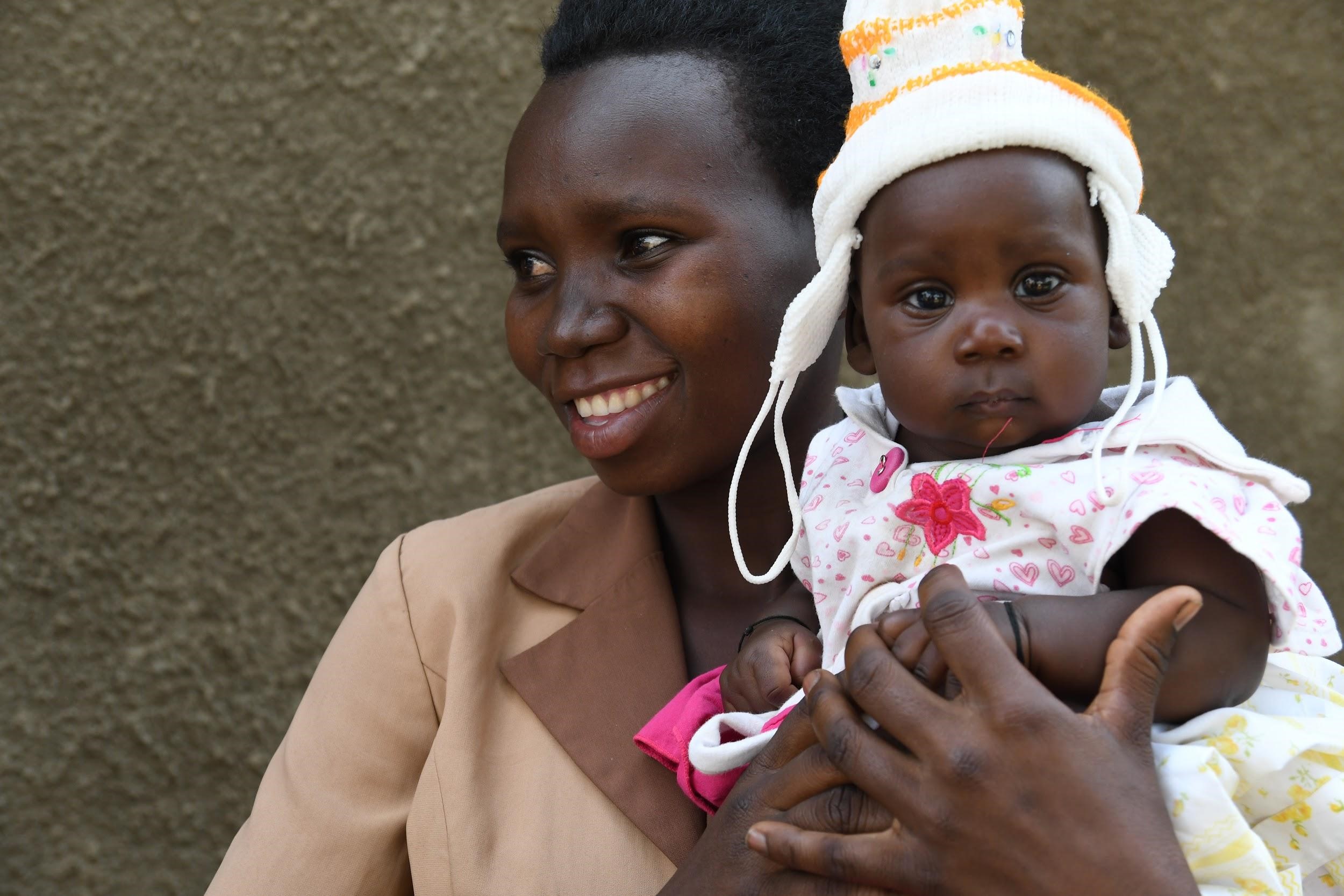 A woman holds her child while smiling.