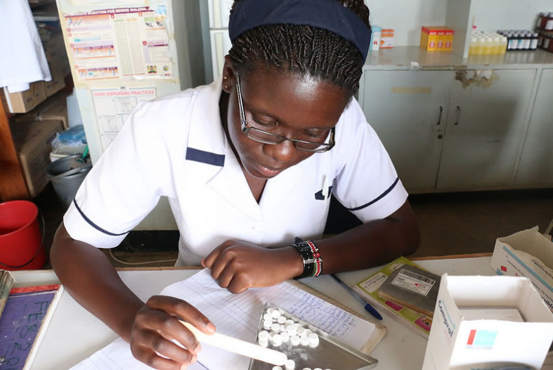 A Kenyan health worker examines pills. Photo credit: Eric Onyiego/USAID-Kenya