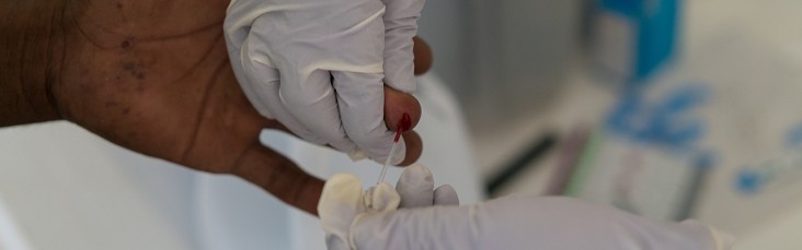 Close-up of the hands of a nurse that hold the hands of a patient while performing a HIV blood test.