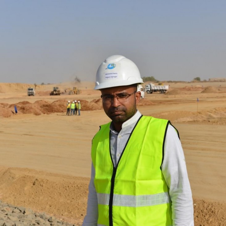 Engineer stands at wastewater pond construction site