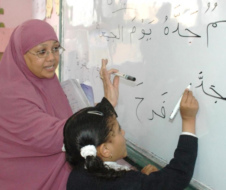 A teacher with a student writing on a whiteboard