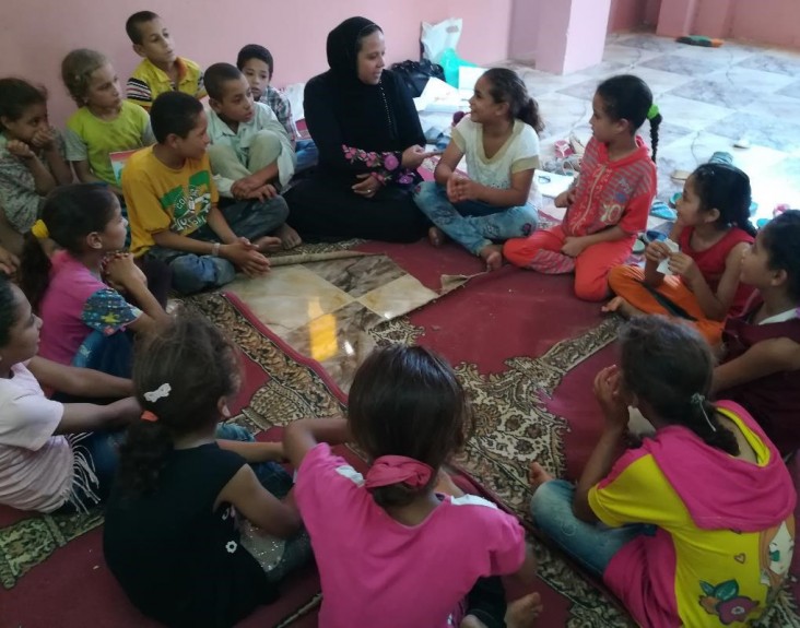 An instructor provides reading instruction for primary school-aged children in rural community schools
