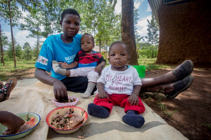 Melanie Atieno feeds her twin one-year-old sons, John Trevin and Peter Ochieng, a meal prepared by her hearth group. 