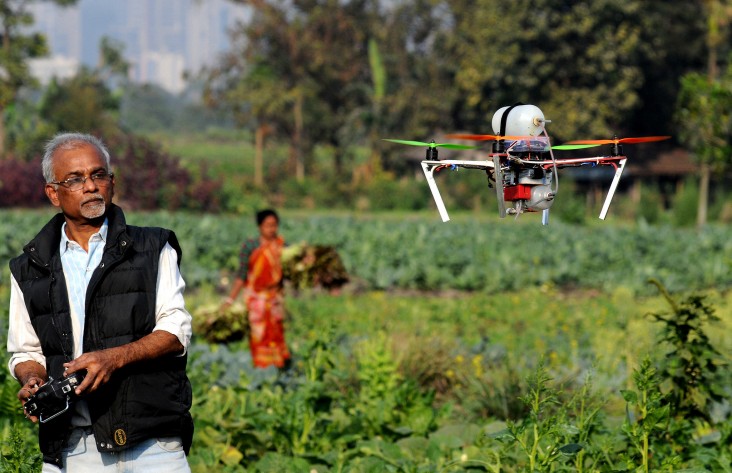 Man operating a drone mapping fields with GIS technology in India