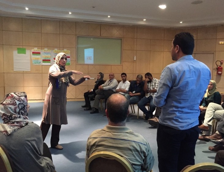 A participant in the USAID Libya Gender & Elections BRIDGE workshop engages men and women in discussion.