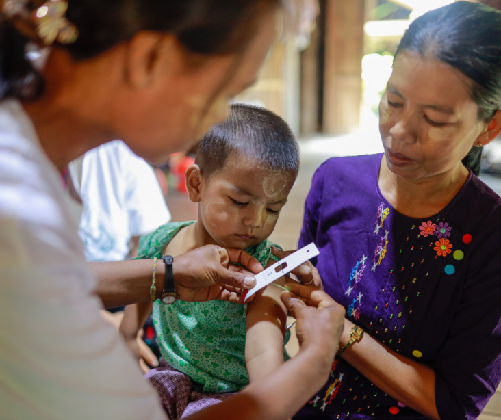 Daw Lei Lei Mu (L), volunteer of Village Health Committee (VHC) measures body size of Mg Hein Thu San (C), son of Daw Khin Mar Swe (R) in Myaychar village, Kyan Khin township, Myanmar.