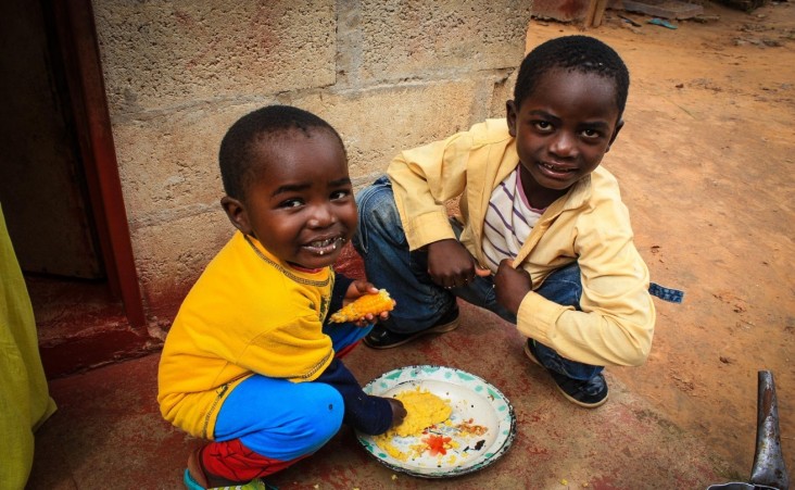 Two young boys eat outside their home