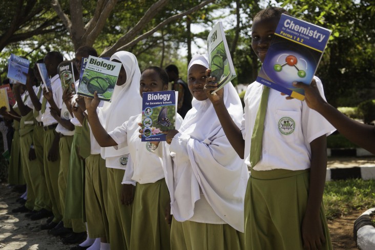 Girls hold up textbooks donated by USAID at a school in Dar es Salaam.
