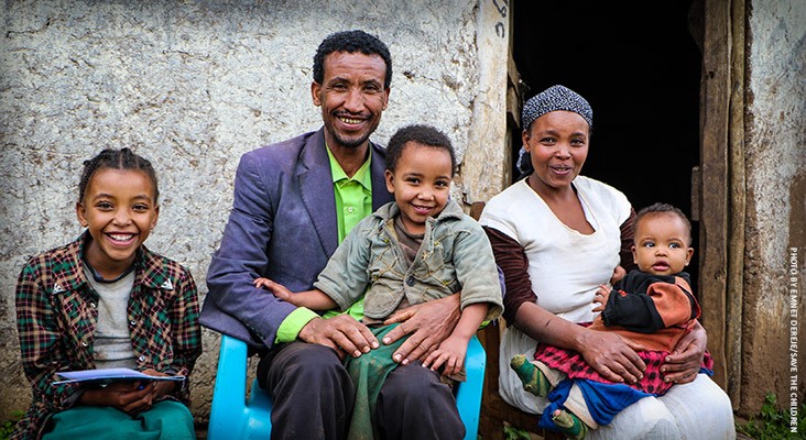 Image of a family who helps their daughters learn to read under USAID programs.