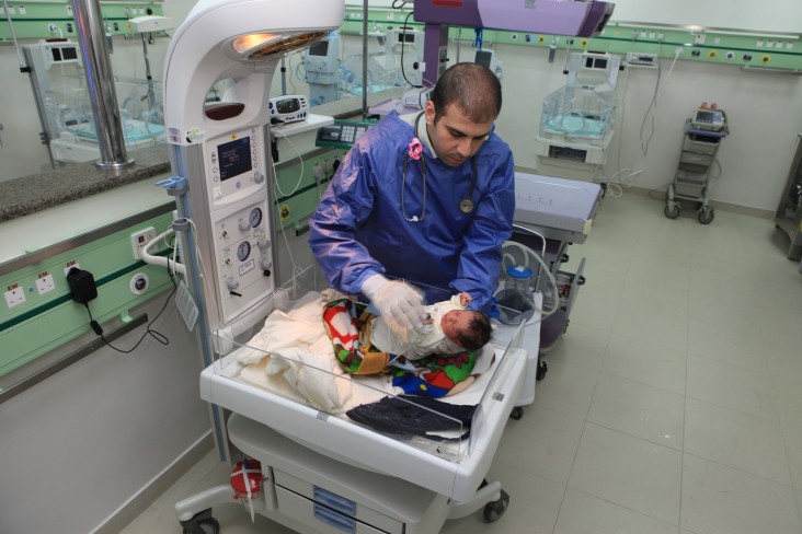 A healthcare worker treats a baby in a hospital room. 