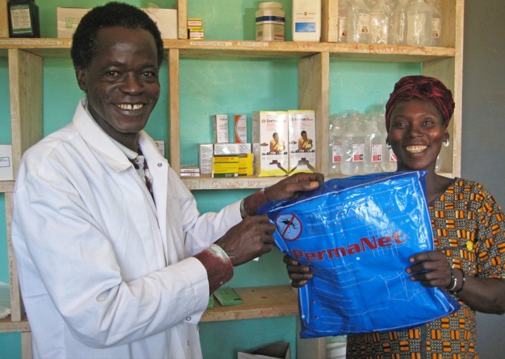 Malian health worker hands over a mosquito net