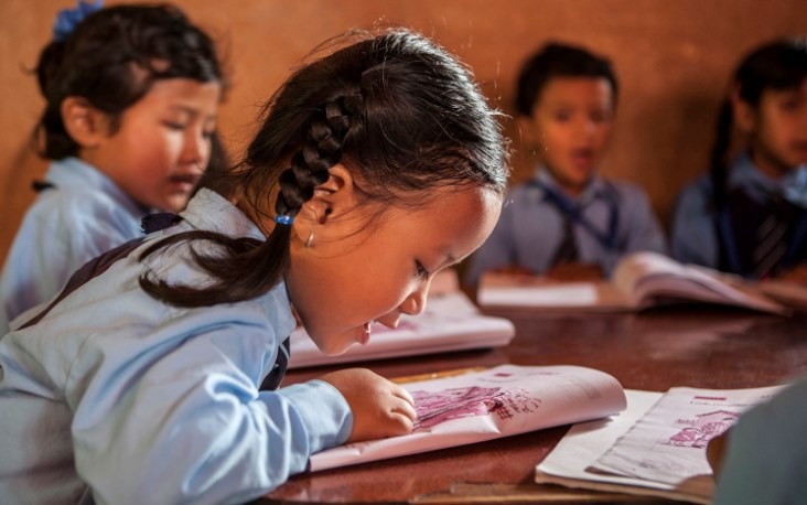 Image of young Nepali girl reading text book