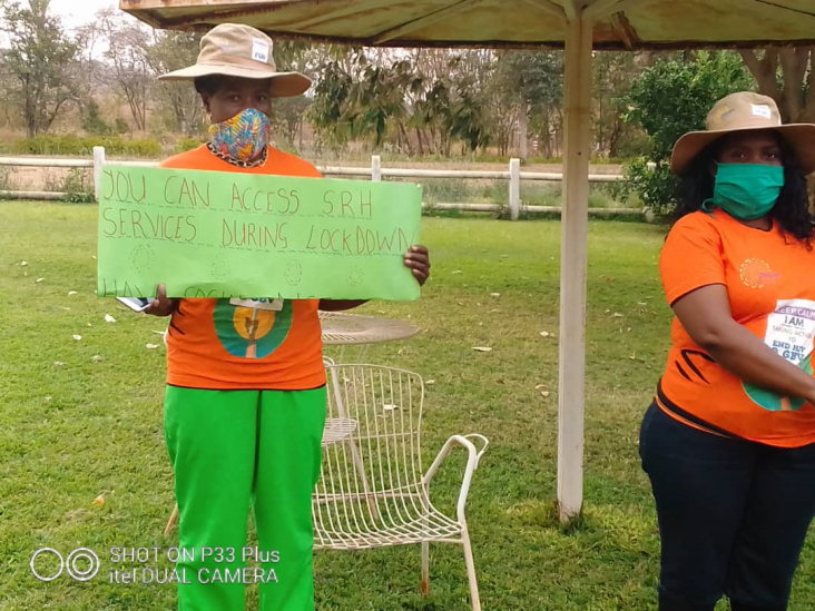 Two DREAMS Ambassadors hold a sign to raise awareness about the rising issue of GBV in their community due to COVID-19 lockdowns.