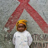 A young boy standing in front of a red ribbon painted on the wall.
