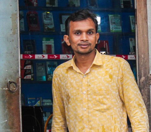 Saiful Islam greets visitors outside his electrical shop. 