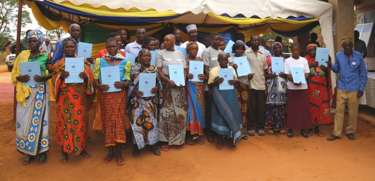 Landholders in Kinywang’anga village hold up their newly received certificates of customary right of occupancy.