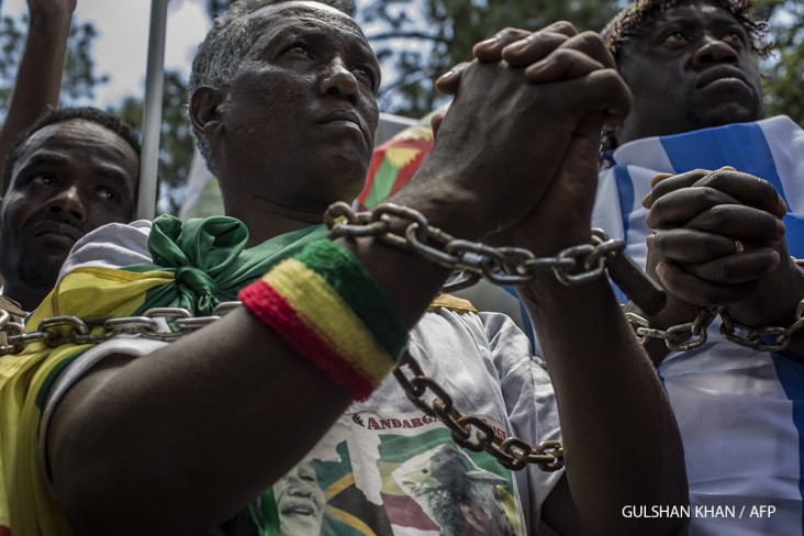 Members of the Africa Diaspora Forum (ADF), civil society organisations, churches, trade unions and other coalitions wear chains and shout slogans during a demonstration against the slave trade and human trafficking in Libya on December 12, 2017 at the Union Buildings in Pretoria. - The UN Security Council on December 7 said reports that migrants detained in Libyan camps were being sold into slavery could amount to "crimes against humanity" in a joint statement of condemnation. (Photo by GULSHAN KHAN / AFP)