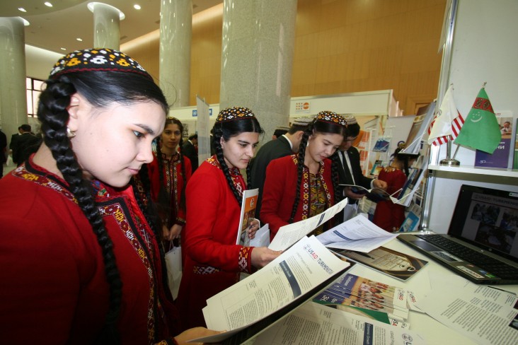 Young women review USAID materials at the Turkmenistan Ministry of Foreign Affairs expo.