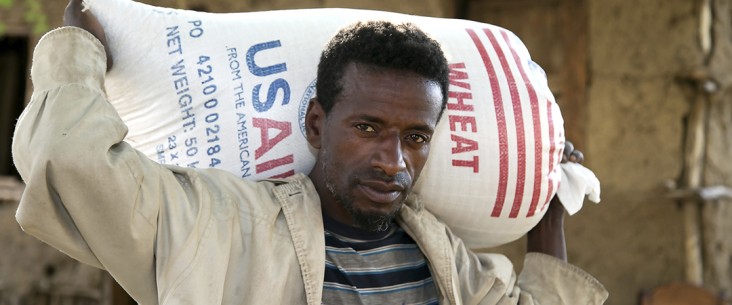 A man carries a bag of wheat from USAID