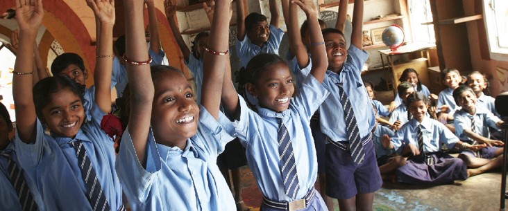 School children smiling with hands raised