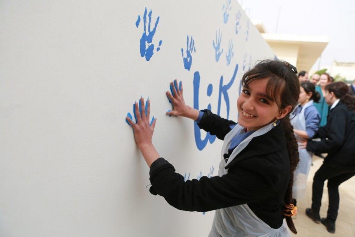 Students at an Irbid Governorate school stamp their hands on a cistern that will help the school build its own water reserves. 