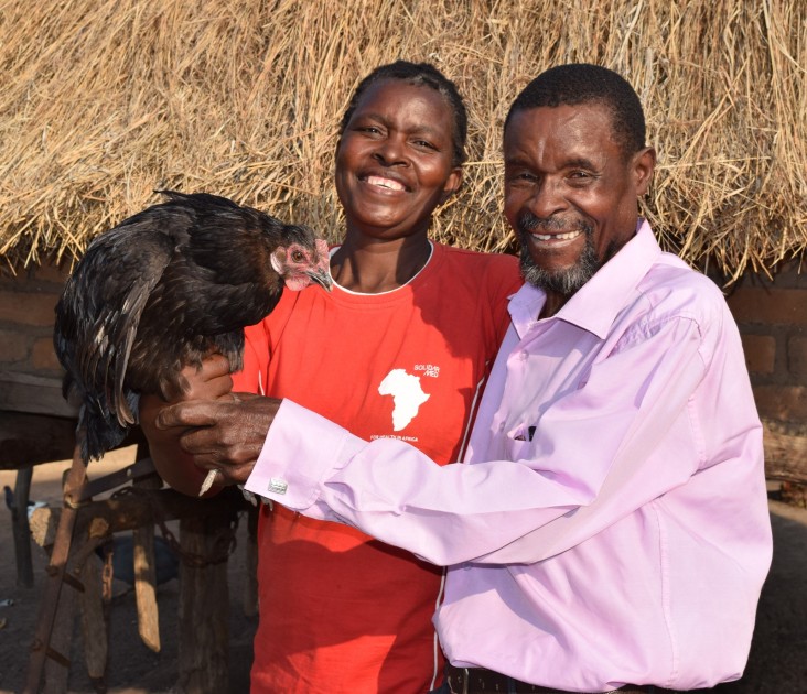 Gosha Zimhatye and his wife show off a prize hen from their poultry project.
