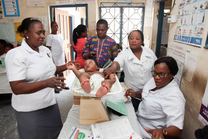 Nurses carry out standard checks to evaluate a child's health, noting his weight and other measurements. Photo credit: Frank Ribas for Communication for Development Ltd.