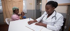 A nurse takes notes while a mother and her child site nearby.