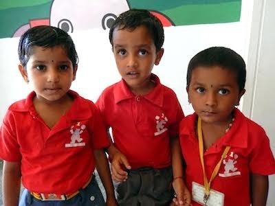 Three smiling young children in school uniforms