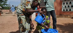 A woman helps a child with handwashing
