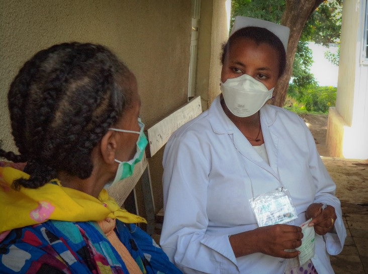 A health care worker checks up on a patient with TB.