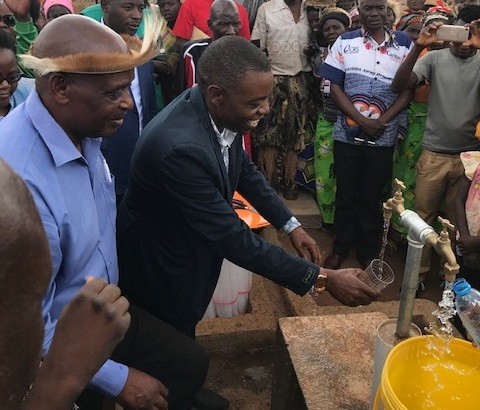 A local chief looks on as Zambia’s Deputy Permanent Secretary for Eastern Province Japhet Lombe officially commissions a rural community water system developed with USAID support.