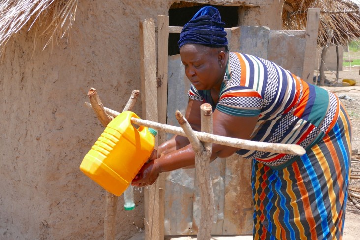 A woman in Ghana demonstrates proper handwashing by using soap and a tippy tap