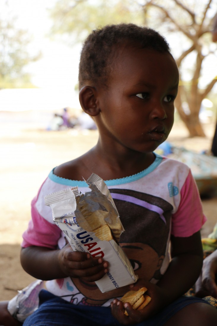 Robert, 2, eats high-energy biscuits after arriving in Uganda