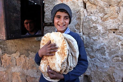 Syrian youth holding bread.