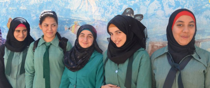 Girls in Jerash pose in front of their school’s storage tank that is painted to look like an aquarium.