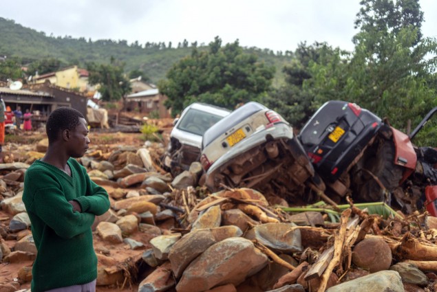 A man stands next to the wreckage a vehicles washed away on  March 18, 2019 in Chimanimani, eastern Zimbabwe, after the area was hit by the cyclone Idai. - A cyclone that ripped across Mozambique and Zimbabwe has killed at least 162 people with scores more missing. Cyclone Idai tore into the centre of Mozambique on the night of March 14 before barreling on to neighbouring Zimbabwe, bringing flash floods and ferocious winds, and washing away roads and houses. (Photo by Zinyange AUNTONY / AFP)