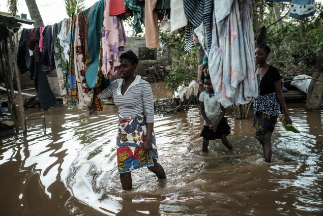 Albertina Francisco (L), and her daughters Rosita Moises Zacarias (R), 15, and Joaninha Manuel, 9, walk in flooded waters from their house destroyed by the cyclone Idai as they go to seep in a shelter in Buzi, Mozambique, on March 22, 2019.