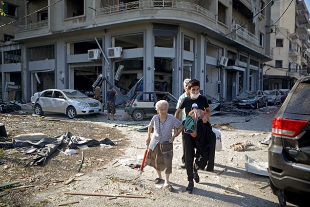 A woman is evacuated from the partially destroyed Beirut neighborhood of Mar Mikhael on August 5, 2020 in the aftermath of a massive explosion in the Lebanese capital.