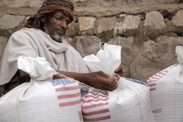In Aje, a man ties his family's ration bags tightly to make sure nothing will be spilled on the journey home. 