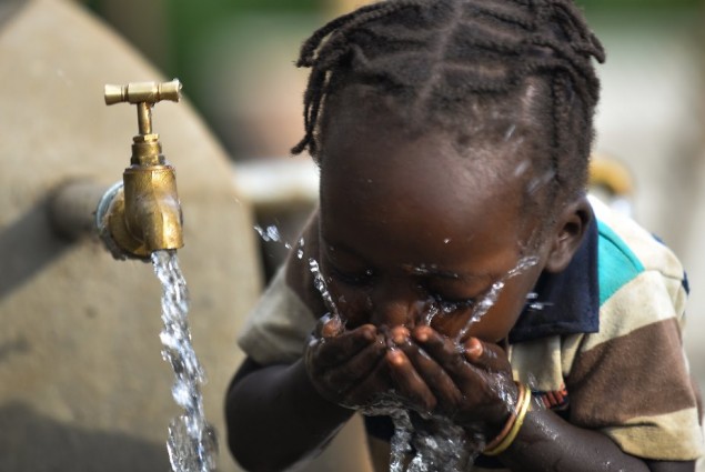 Image of girl in Ethiopia drinking from water tank